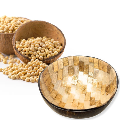 Kokosnuss-Schale mit Perlmuttmosaik neben einer Holzschale mit hellen Körnern