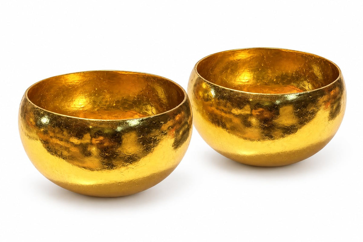 Zwei Kokosschalen mit goldfarbener Außenseite und gerundeter Form
