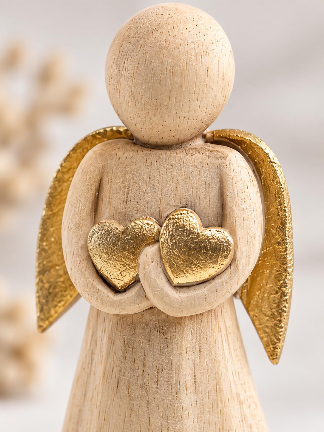 Detailansicht: Helle Engelfigur aus Holz mit zwei goldfarbenen Herzen und goldfarbenen Flügeln