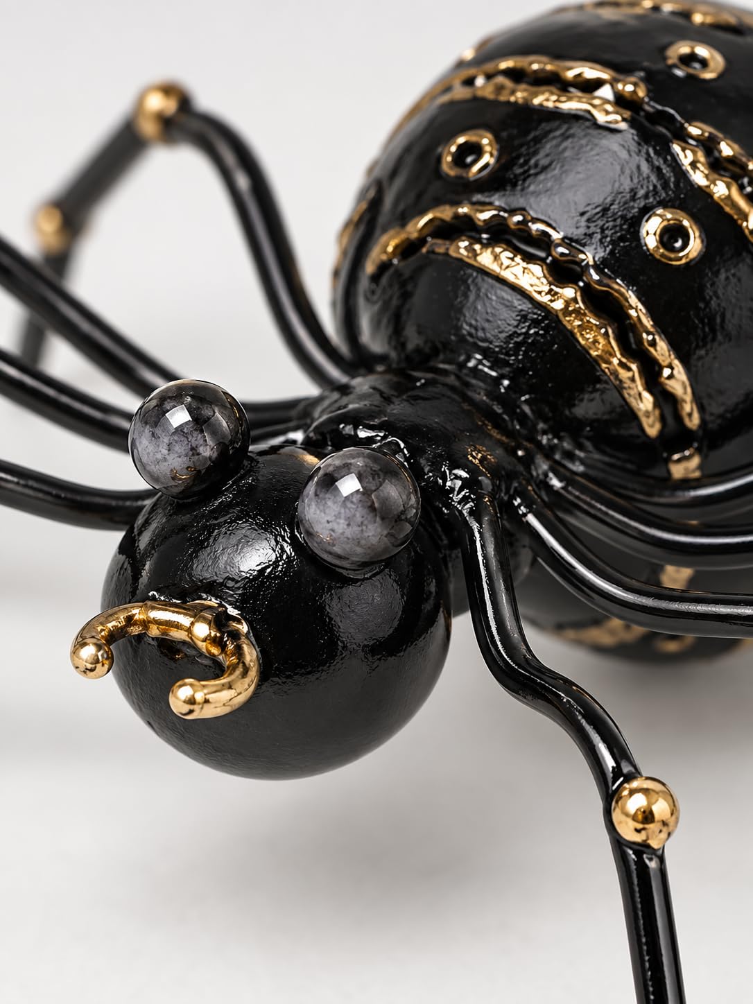 Detailansicht: Schwarze dekorative Metallspinne mit goldfarbenen Verzierungen