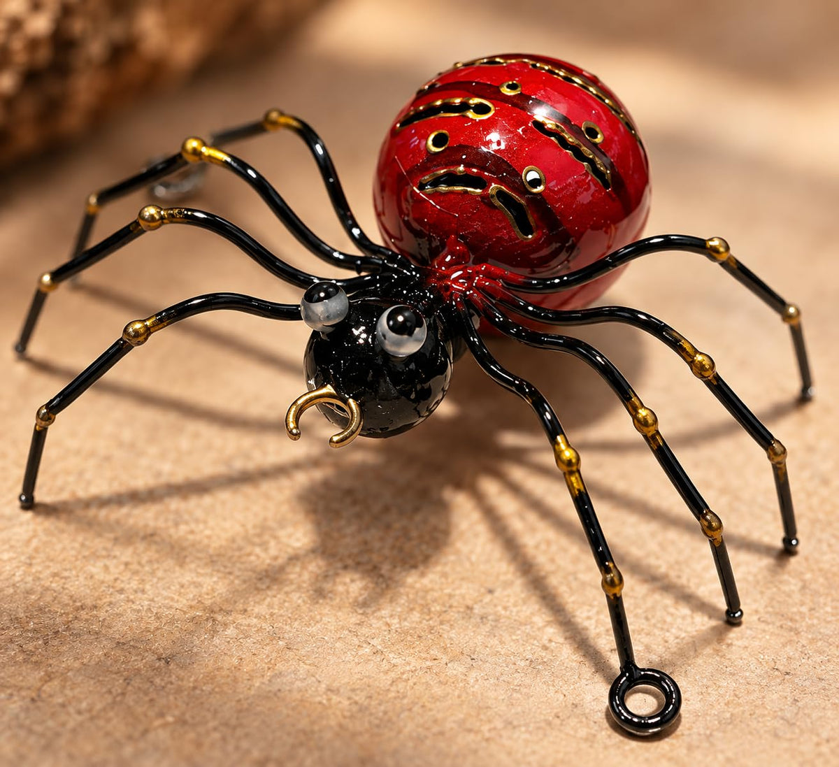 Dekorations- oder Anwendungsbeispiel: Rote dekorative Metallspinne mit schwarzen Beinen und goldfarbenen Details