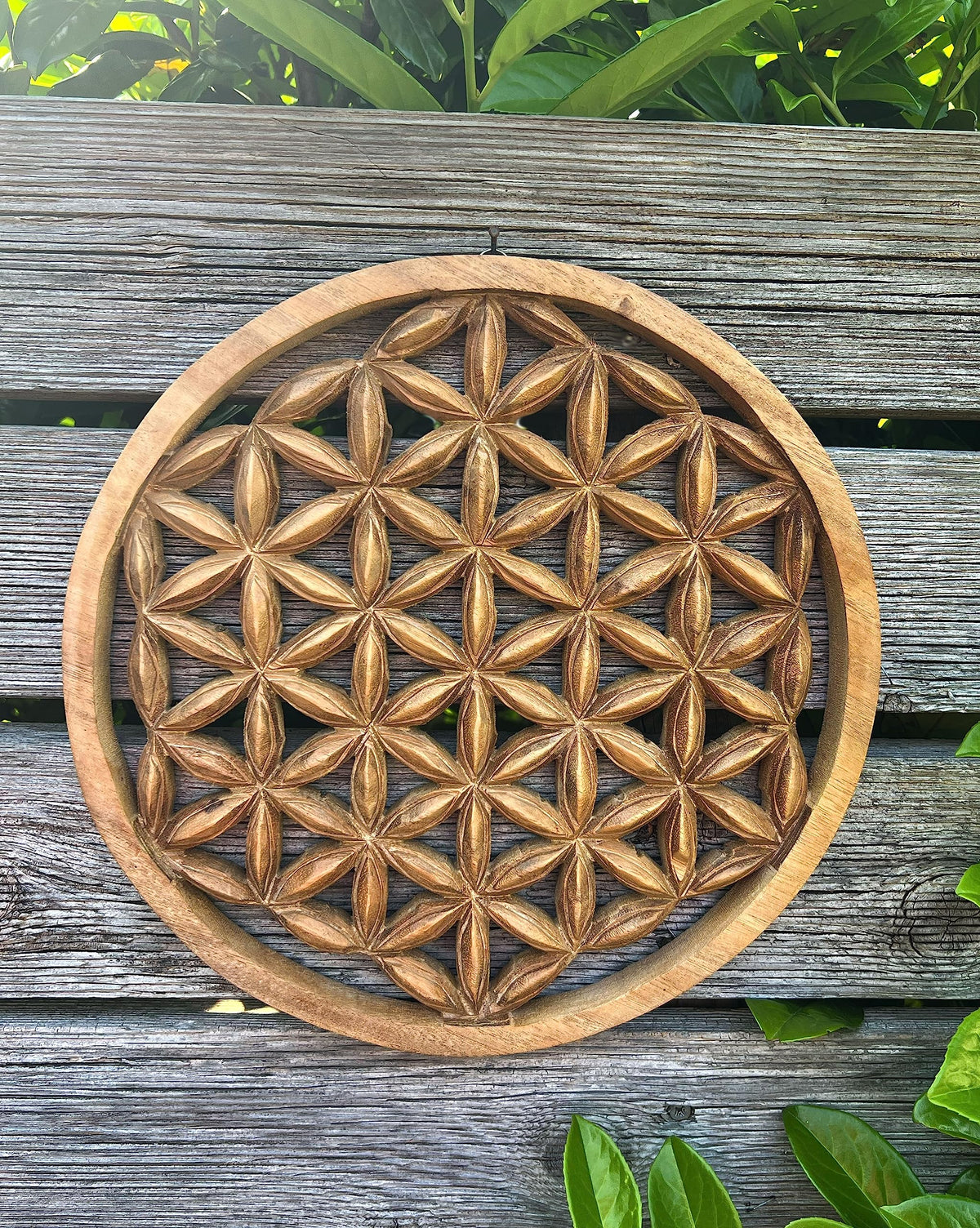 Blume-des-Lebens-Wandbild aus Akazienholz vor verwitterten Holzplanken