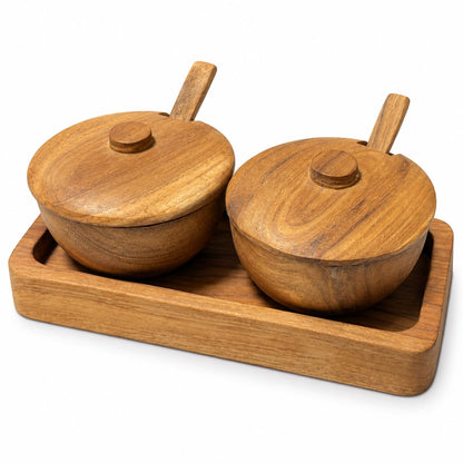Zwei runde Teakholz-Gewürzschalen mit Deckeln und Löffeln auf einem Holztablett